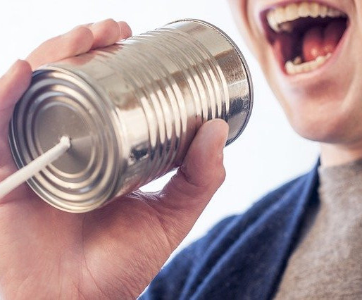 Man shouting into a tin can and string phone.