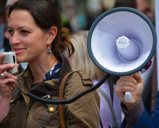 Woman using a megaphone in a crowded space.