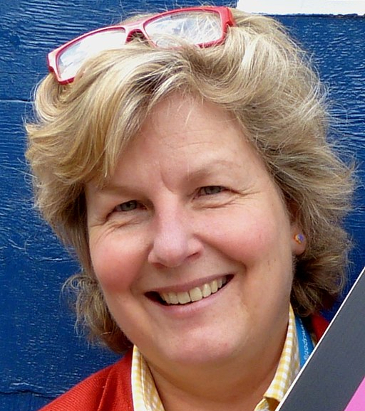 A smiling Sandi Toksvig with her glasses on her head. 
