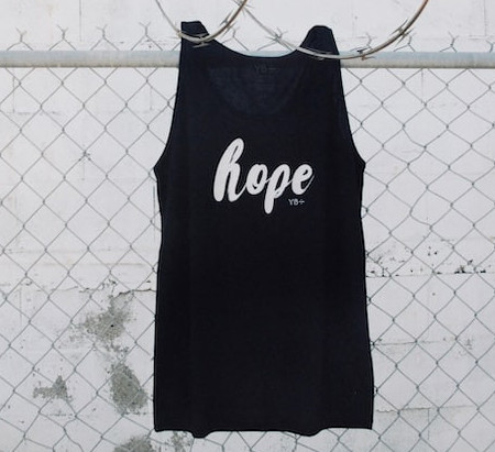Hanging on a wire fence, a black vest shirt with the word 'hope' in white.