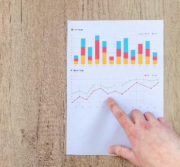 Pointing at a sheet of paper with graphs on it. 