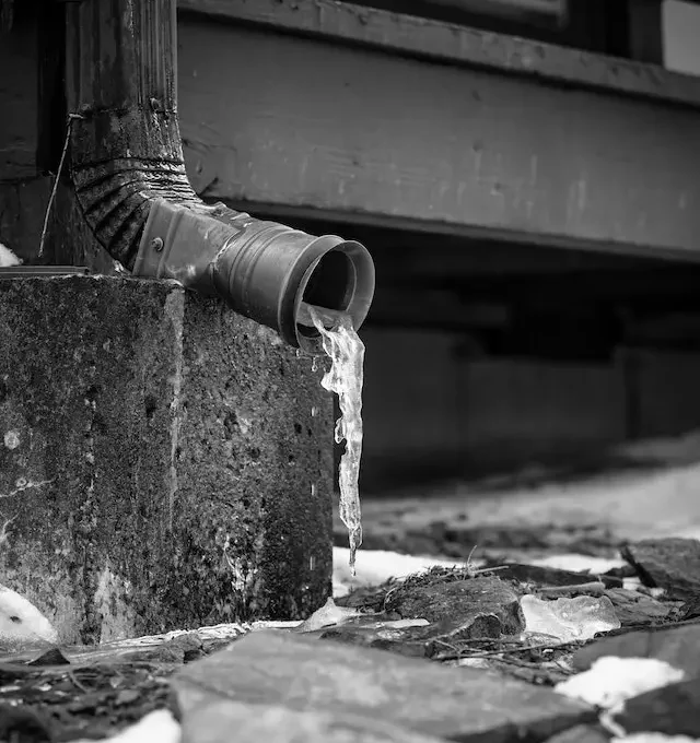 A gutter downpipe with water coming out of it.