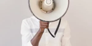 Man standing with a large megaphone in front of his face.