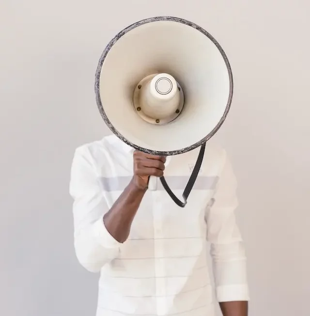 Man standing with a large megaphone in front of his face. 