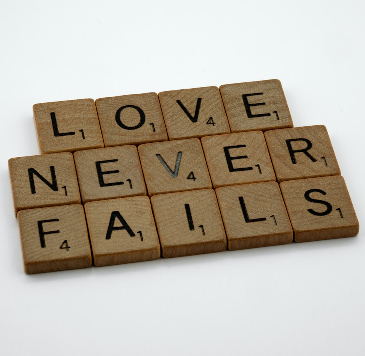 Scrabble letters spelling out: "Love Never Fails". 