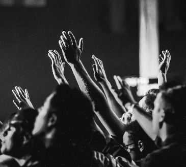 Black and white photo of people with hands raised in the air. 