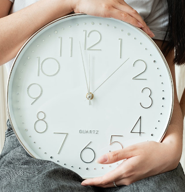 Holding a large analogue clock. 