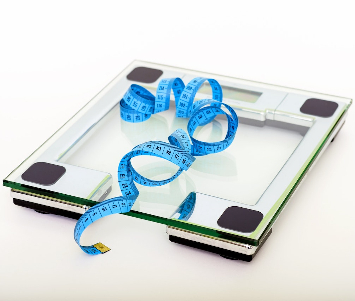 Bathroom weighing scales with a blue measuring tape on the plate. 