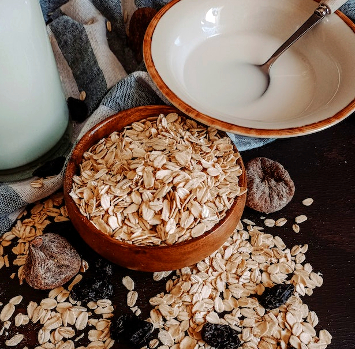 A bowl of oats with some spilled on the countertop. 