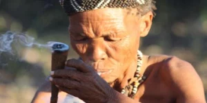 Tribal woman sitting down smoking a chillum.