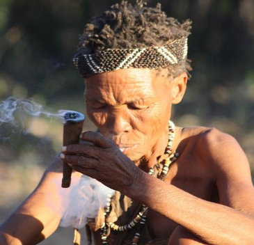 Tribal woman sitting down smoking a chillum. 