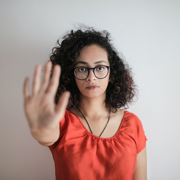 Woman in a red top holding her hand up at the camera to indicate 'stop'. 