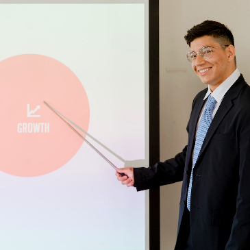 Dodgy looking marketing type pointing at a whiteboard with some nonsense on there about growth. 