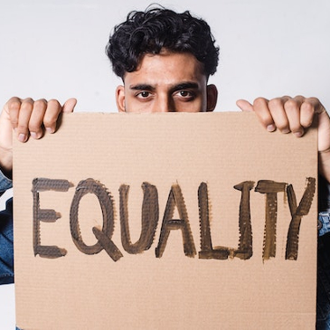 Man holding up a cardboard sign saying 'Equality'. 