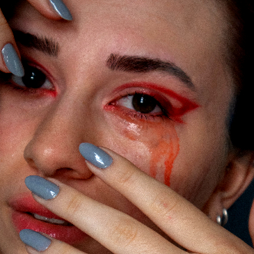 Close up of a woman with red make up running down her face. 