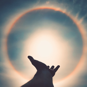 Extending a hand out towards a dramatic sun halo. 