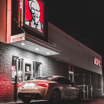 Expensive car waiting at a KFC drive through at night. 