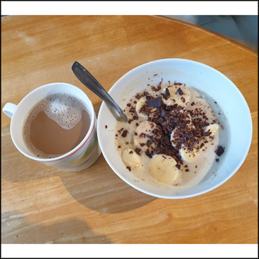 A bowl of porridge with banana, dark choc chips and Vedge vanilla protein powder shake on top.
