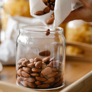 Pouring whole almonds into a glass. 