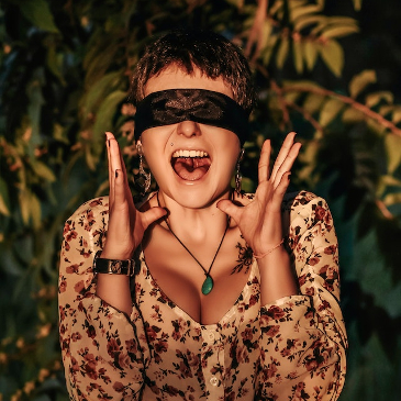 Blindfolded woman screaming with plants behind her. 