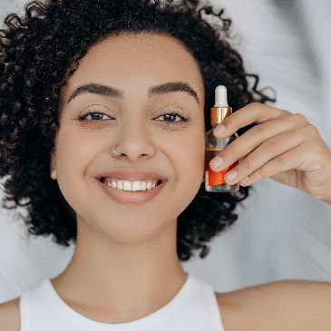 Woman holding up a bottle of essential oil. 