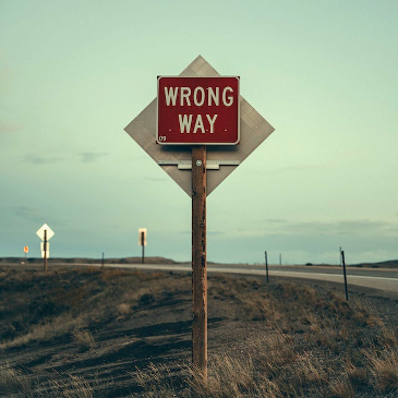 A sign on the highway at dusk saying "Wrong Way". 