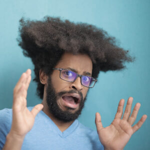 Man with his hands in the air and a scared look on his face.