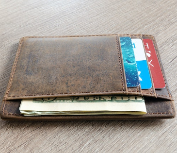 Brown leather wallet containing bank cards and some cash. 