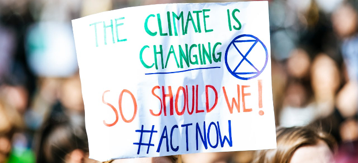 A banner at a climate change rally reading 'The climate is changing, so should we! #act now' 